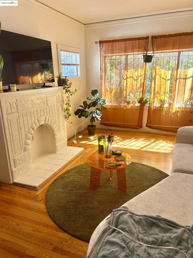 Living area with wood finished floors, crown molding, and a fireplace