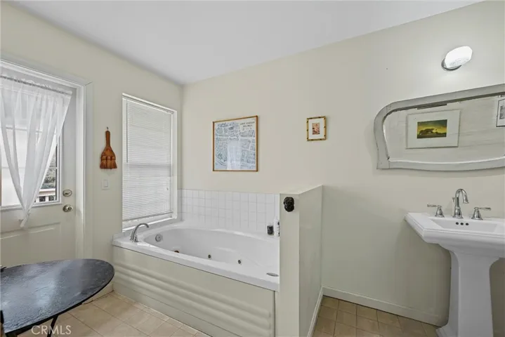 Jetted tub in primary suite with outdoor access to deck.