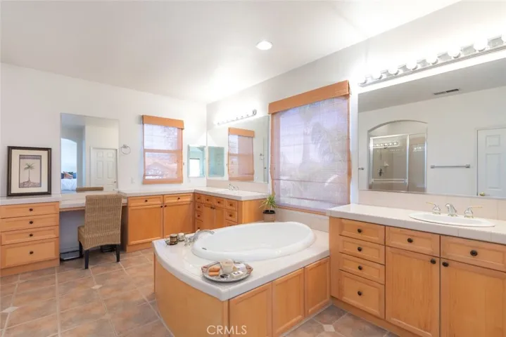 Stunning bathroom with a spacious vanity setup, separate sinks, and a soaking tub.