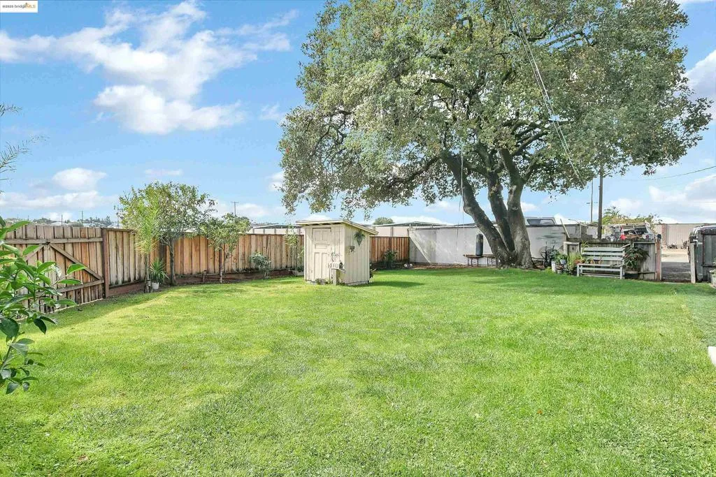 Fenced backyard featuring a storage unit