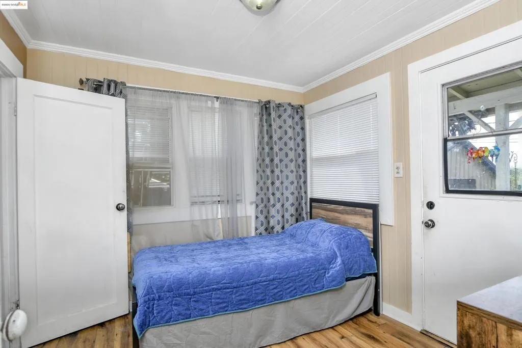 Bedroom featuring wood finished floors and crown molding