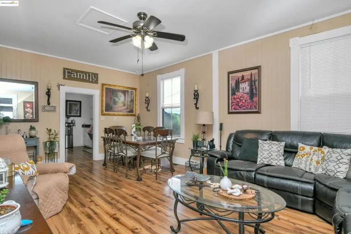 Living area featuring crown molding, wood finished floors, a ceiling fan, and wooden walls