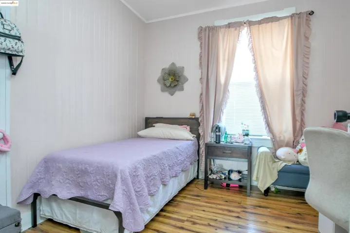 Bedroom with wood finished floors and crown molding