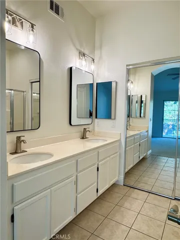 Dual sink vanity in primary bathroom with walk-in closet