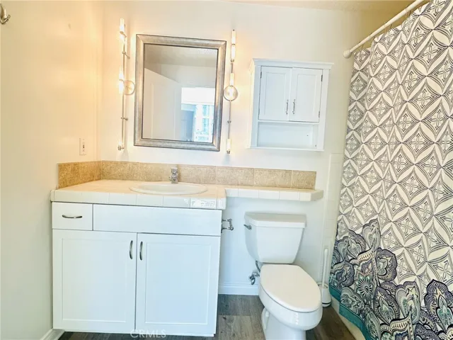 Primary bathroom angle showing tile countertop and storage.