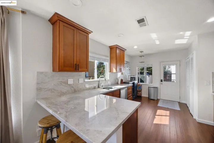 Kitchen with brown cabinetry, tasteful backsplash, a breakfast bar, a peninsula, and dark wood-type flooring