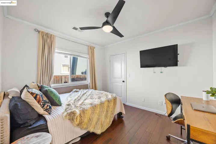Bedroom featuring ornamental molding, dark wood-style floors, a ceiling fan, and an office area