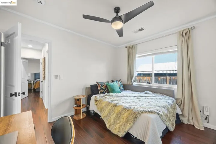 Bedroom featuring ornamental molding, dark wood-type flooring, and a ceiling fan