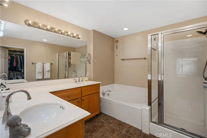 Primary bathroom with dual vanities, an oversized tub, plus a shower.