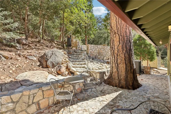 Terraced rock patio with stone steps and mature pines—ideal outdoor entertaining.