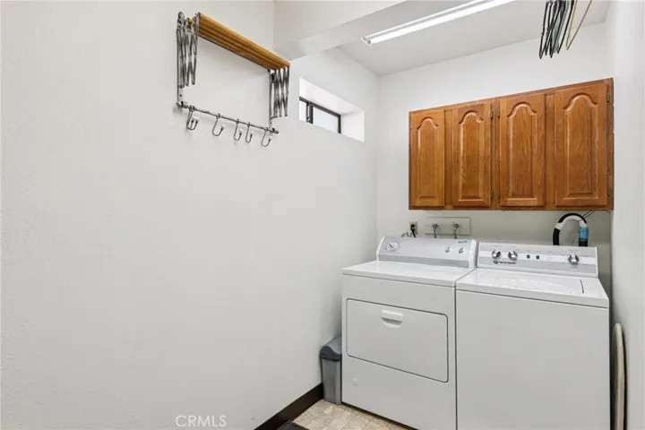 Dedicated laundry room with cabinets and drying racks—includes durable Speed Queen set.