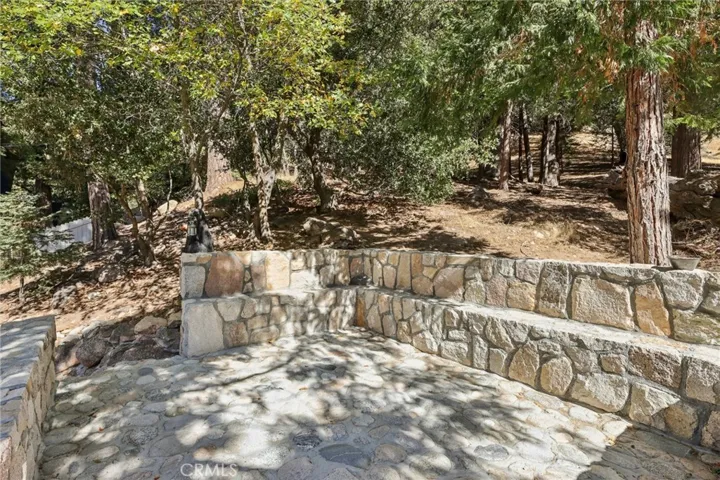 Upper rock terrace with built-in seating—gather under the trees.