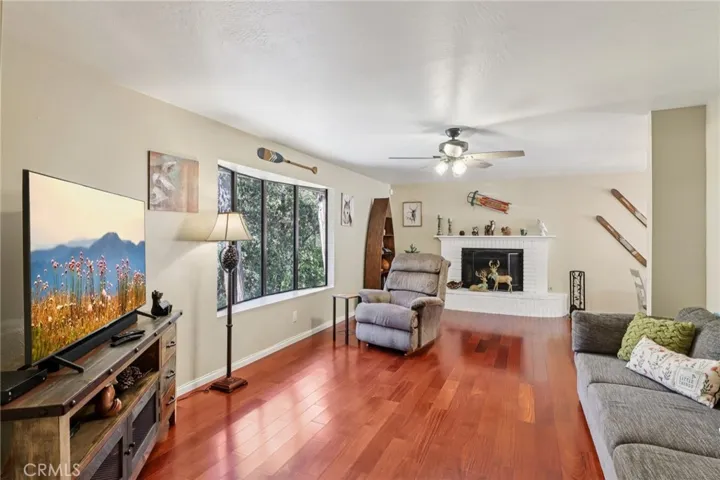 Sun filled living room with bay window and white brick fireplace - classic lodge feel.