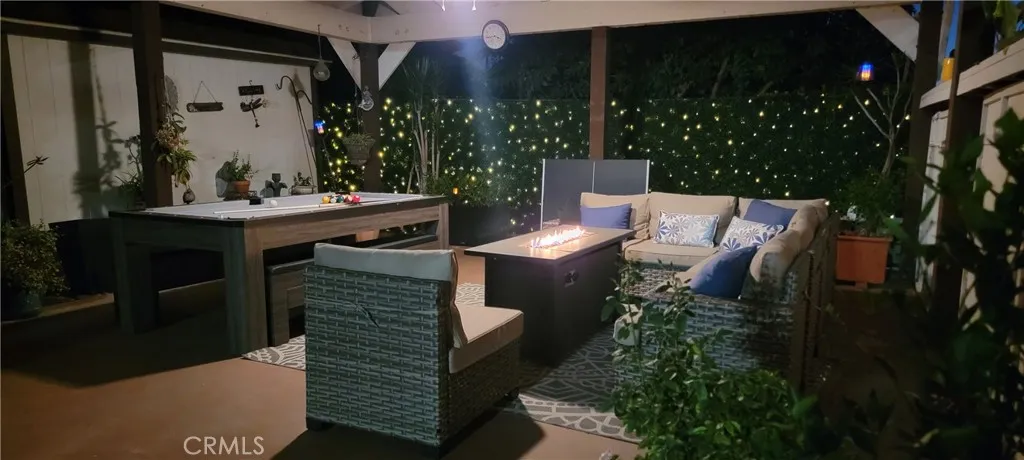 Closeup of covered 400 sq. ft carport/patio area wi/ pool/pingpong/dining table and firepirt sectional seating area with fan light.