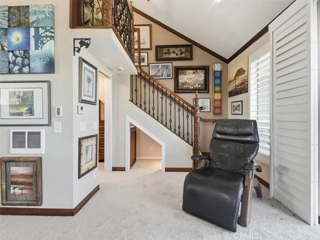 Custom stairs with ornate wood-and-iron railing lead to the loft, featuring matching crown molding, baseboards, and LED-lit area beneath the stairs.