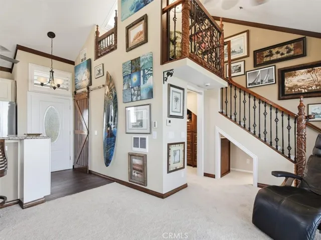 From the balcony you’re welcomed into a spacious living area with a vaulted ceiling and stairway to the loft, accented by a custom sliding door and ornate banister. Rich crown molding and continuous floorboards unify the interior in timeless elegance.
