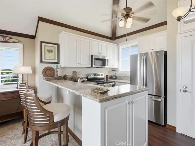 From the kitchen bar, enjoy sunlit southern views streaming through plantation-shuttered windows, highlighting the chef’s kitchen and sleek appliances.
