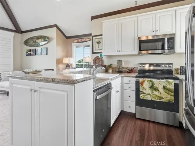 Chef’s kitchen with south-facing window, plantation shutters, sleek appliances, and a kitchen bar with stunning natural light.