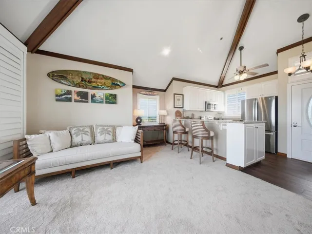 View from the stairs overlooking the open living area and kitchen bar, with south-facing windows, plantation shutters, and abundant natural light.