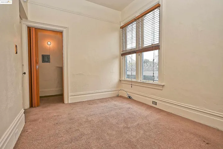 Unfurnished room featuring light carpet and a textured wall