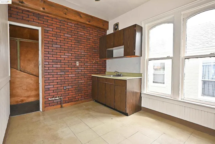 Kitchen featuring brick wall, light countertops, and dark brown cabinets