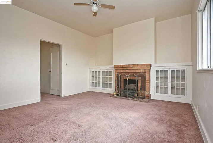 Unfurnished living room with a fireplace, carpet floors, and a ceiling fan