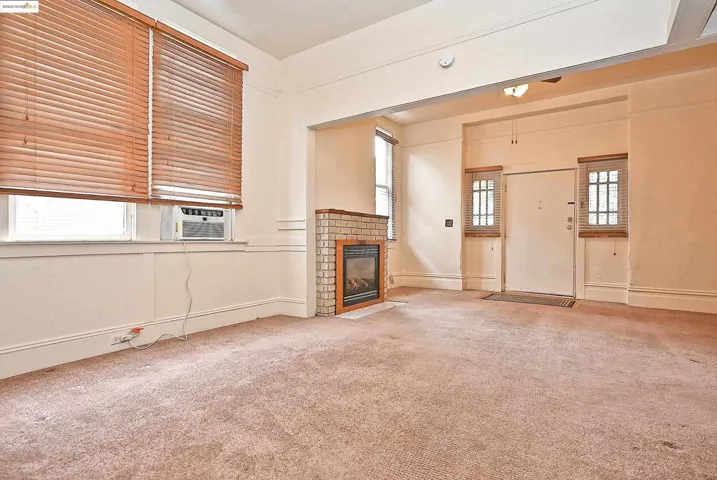 Unfurnished living room with a tiled fireplace, carpet, and cooling unit