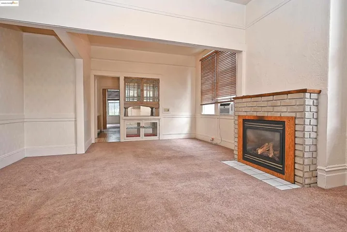 Unfurnished living room featuring a decorative wall, a fireplace, light colored carpet, and a wainscoted wall