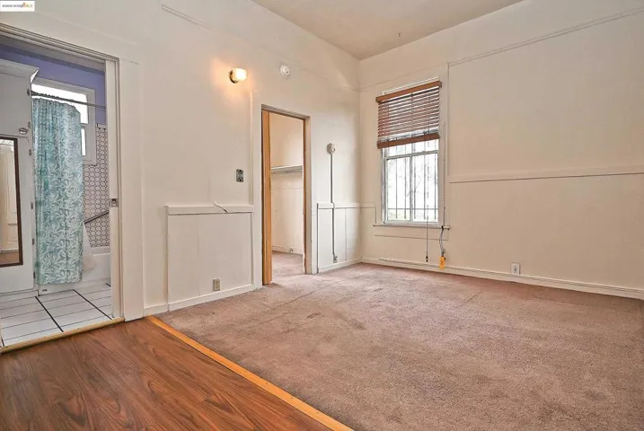 Carpeted spare room featuring wood finished floors and baseboards