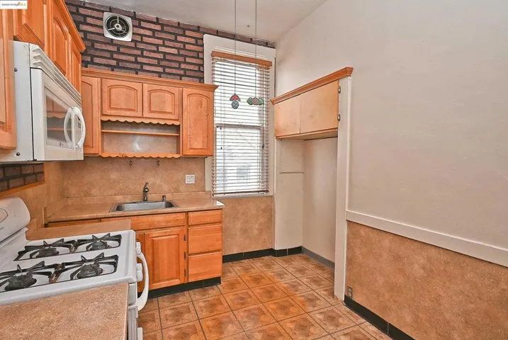 Kitchen with white appliances, light countertops, light tile patterned floors, open shelves, and decorative light fixtures
