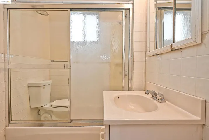 Full bath featuring tile walls, a stall shower, and vanity