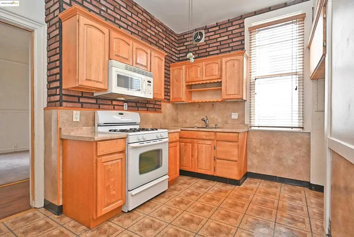 Kitchen with white appliances, light countertops, decorative backsplash, open shelves, and light tile patterned floors