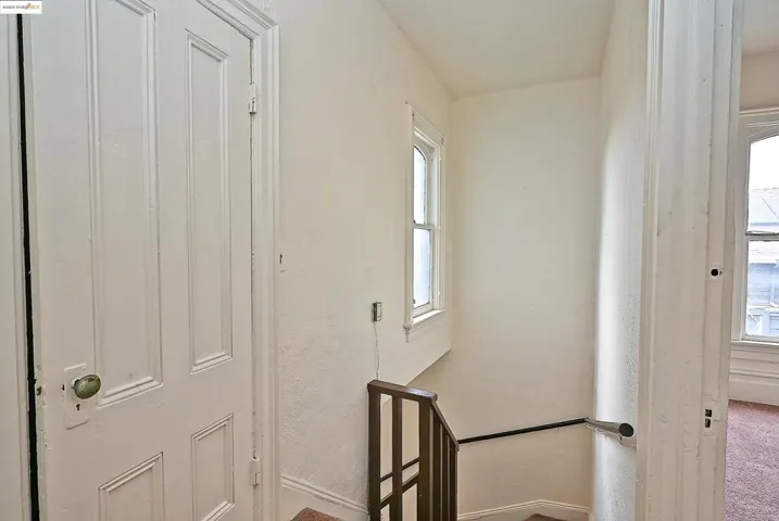 Hall featuring plenty of natural light, an upstairs landing, a textured wall, and carpet flooring