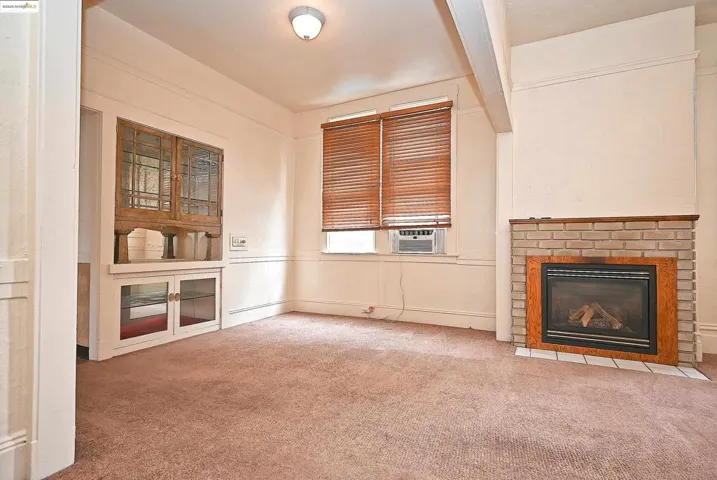 Unfurnished living room with carpet floors, beam ceiling, and a brick fireplace