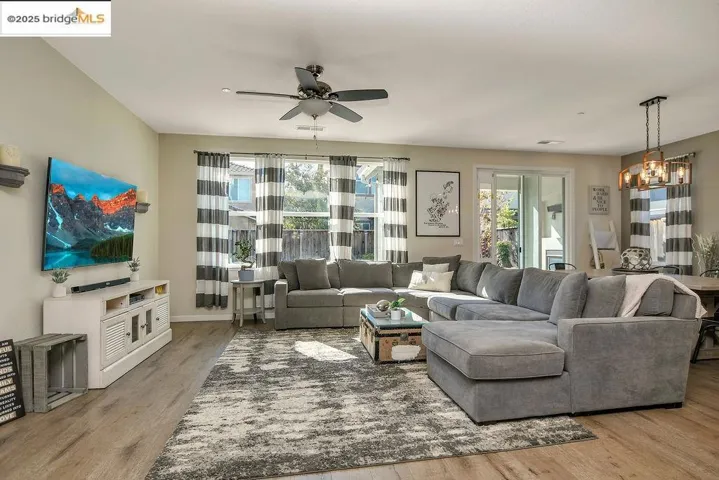 Living area with light wood finished floors, a chandelier, and ceiling fan