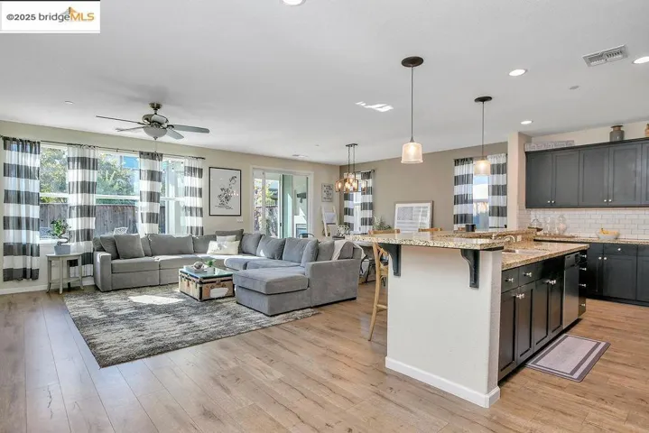 Kitchen featuring a breakfast bar, decorative backsplash, light stone counters, open floor plan, and recessed lighting