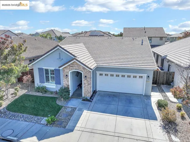 View of front of home featuring stone siding, stucco siding, concrete driveway, solar panels, and a tiled roof