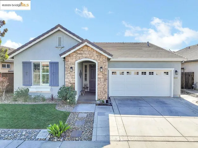 Ranch-style home featuring stucco siding, driveway, an attached garage, stone siding, and a tile roof