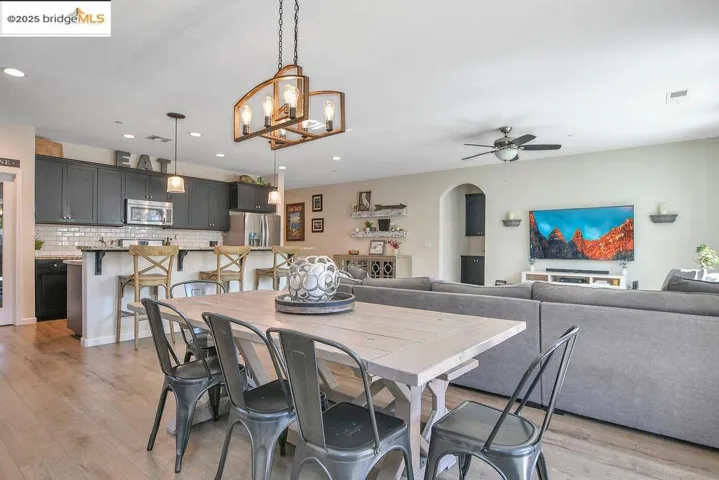 Dining space featuring arched walkways, light wood-style floors, a ceiling fan, a chandelier, and recessed lighting