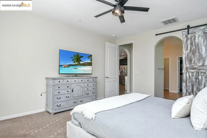 Carpeted bedroom featuring arched walkways and a ceiling fan