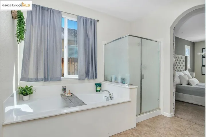 Ensuite bathroom with a bath, plenty of natural light, a stall shower, and light tile patterned flooring