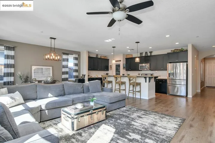 Living area featuring light wood-type flooring, arched walkways, a chandelier, ceiling fan, and recessed lighting