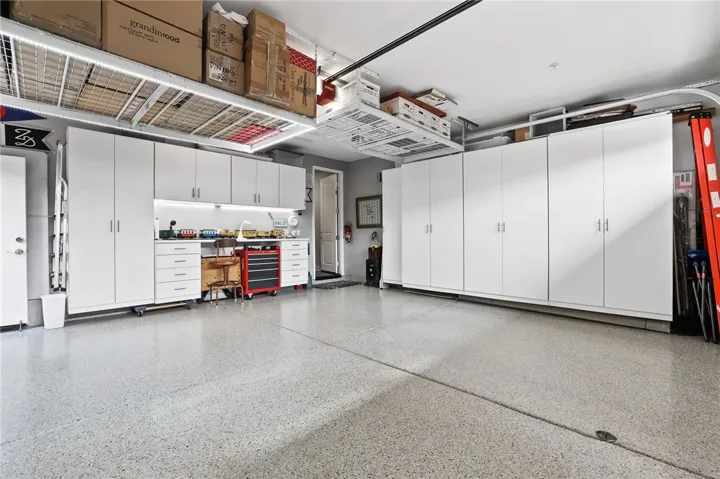 Spacious garage with over head racks,  organized storage space and clean floors.
