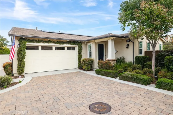 Front exterior view of charming home with well-maintained landscaping and driveway.