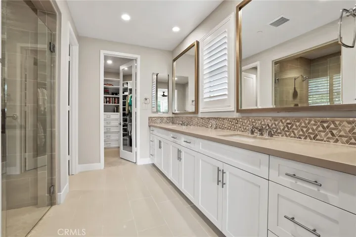 Luxurious bathroom with double vanities, quartz countertops, and large mirrors.