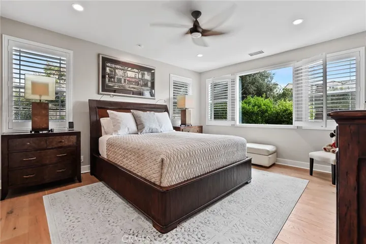 Spacious primary bedroom with ceiling fan, large windows, and neutral decor.