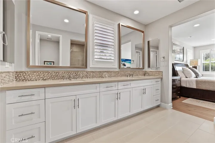 Dual sinks, white vanity, ample storage, and elegant finishes.