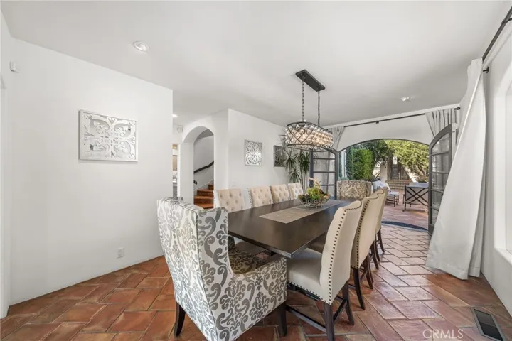 Formal Dining Room-Seats 10 Tufted High-back Chairs/Exquisite Lighting-Crystal Chandelier/French Doors to Exterior Courtyard w/Spanish Tile Carried Throughout for Authentic Old World Feel Indoor/Outdoor Traditional Dining Experience/Kitchen across hall on left
