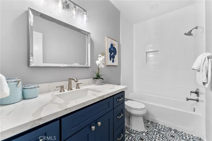 A fabulous updated full bath that also compliments the beach life. New cabinets, quartz counters, custom tile, commode, lighting, mirror, newly painted. Ready for you!