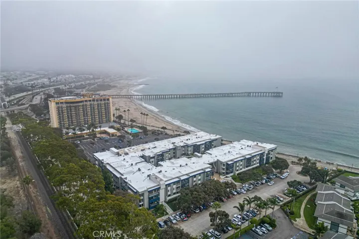 The building with white rooftops is the complex. The unit is on the right side. Parking is available on the right side. The pier is in the near distance. Train tracks in the foreground.